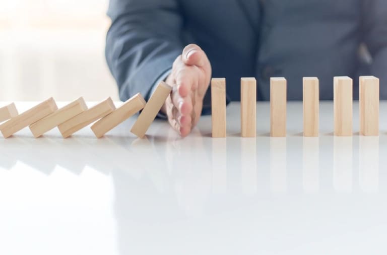 A person is stopping the domino effect on a table.