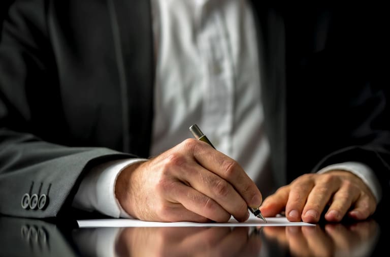 A man writing on paper with pen and ink.