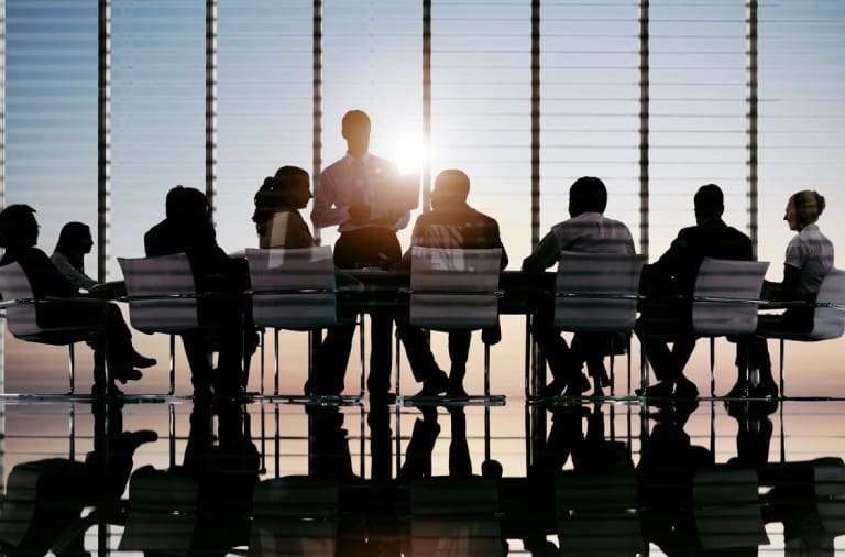 A group of people sitting at a table in front of a window.